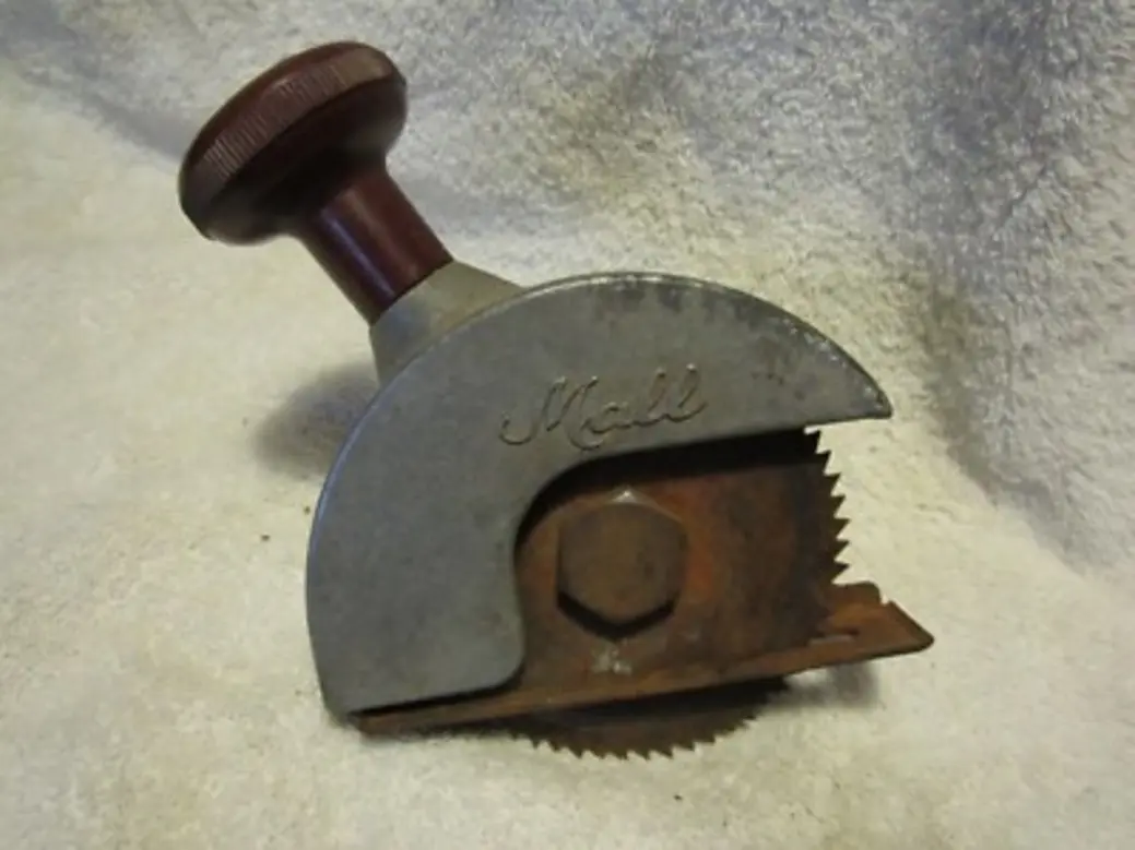 A vintage drill-driven circular saw attachment with a wooden handle and serrated blade.