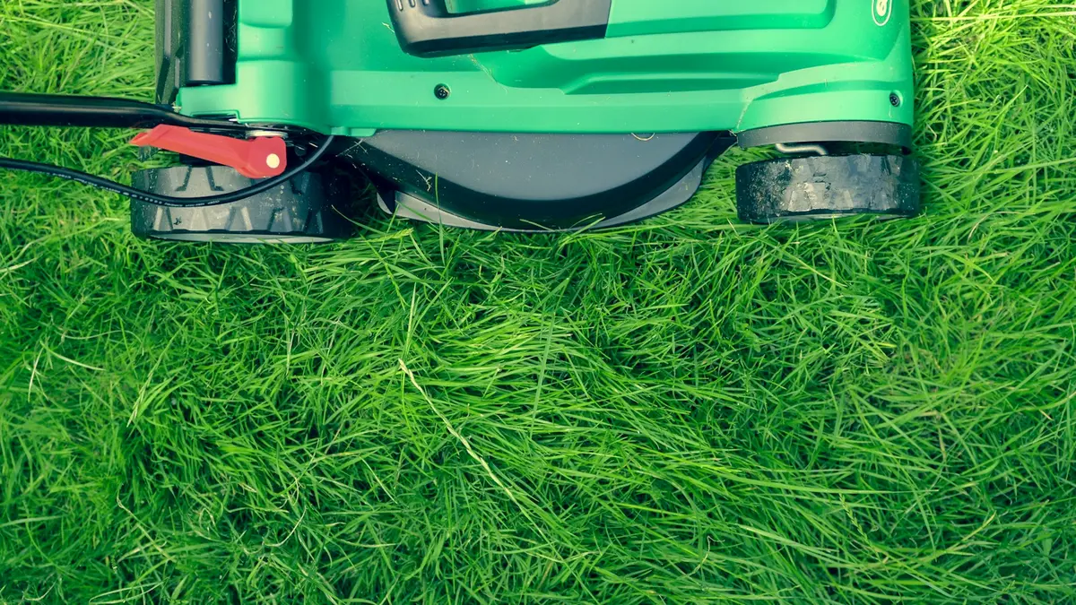 Close-up of a lawn mower deck with grass buildup visible beneath the blades.