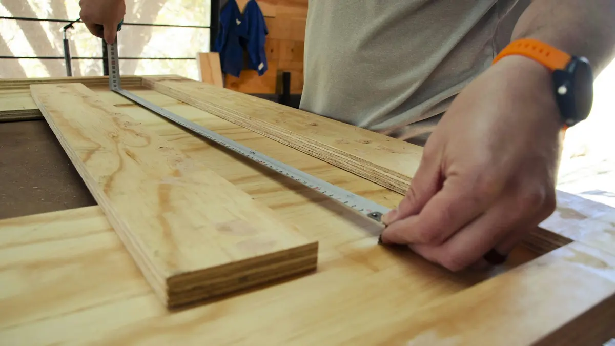 A person using a straightedge to measure plywood with a circular saw nearby.