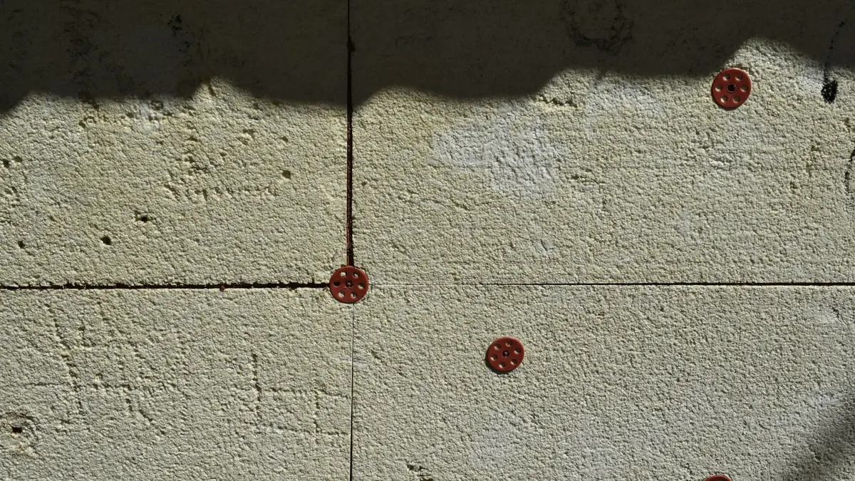 Markings on a wall with three red tile spacers in a grid layout.