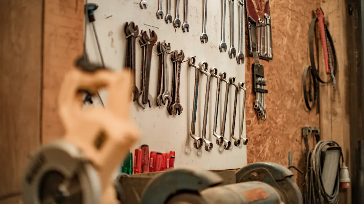 A wall-mounted board displays various wrenches and tools in an organized workshop setting.