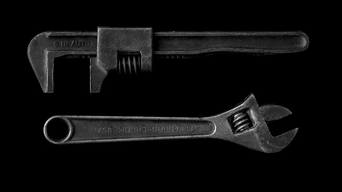 Pliers wrench and adjustable wrench displayed side by side on a black background.