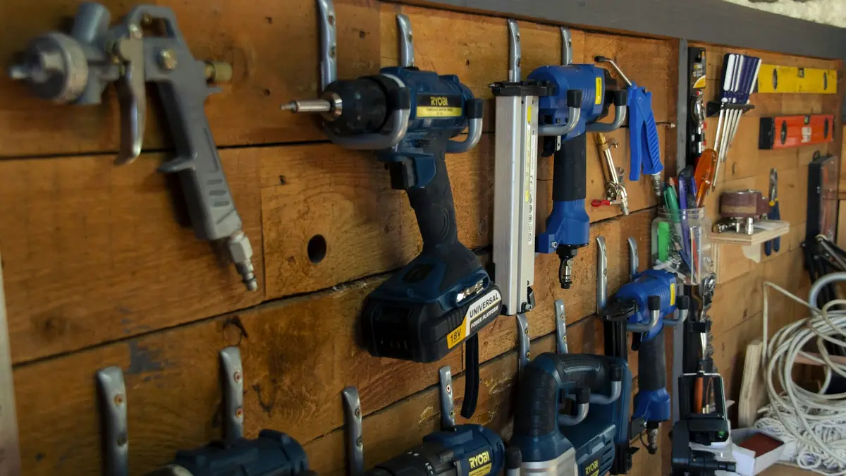 Power tools and accessories neatly organized on a wooden wall with hooks.