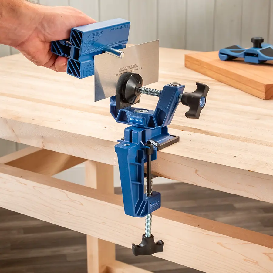 A woodworking clamp with a saw blade attachment securely mounted on a workbench.
