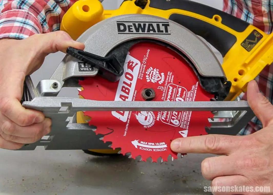 Circular saw with red blade, hand pointing at the blade's rotation direction.